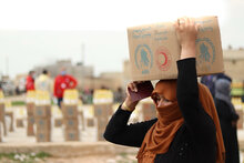 Una donna siriana trasporta sulla testa un pacco di cibo del WFP