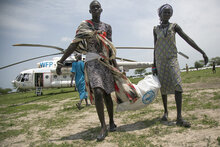 donne trasportano un sacco di cibo scaricato da un elicottero